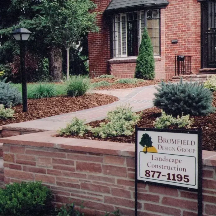 A homeowner adjusts their smart irrigation system schedule on a smartphone, with their beautiful, green lawn visible in the background.